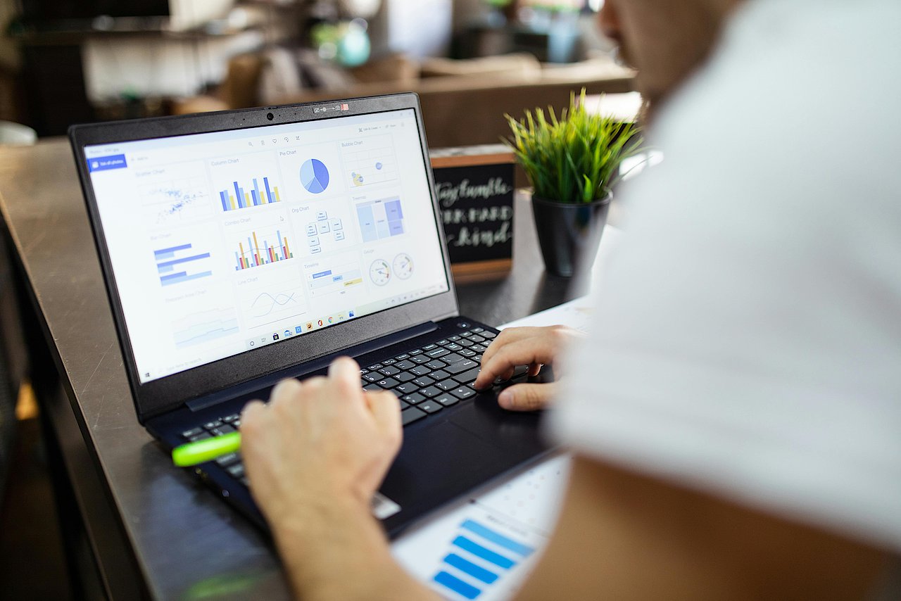 Ein Mitarbeiter vor dem Laptop mit Diagramm, das die Analyse von Kundendaten und die daraus gewonnenen Erkenntnisse visualisiert. Dies unterstreicht die Bedeutung von Datenanalyse für ein effektives CRM.